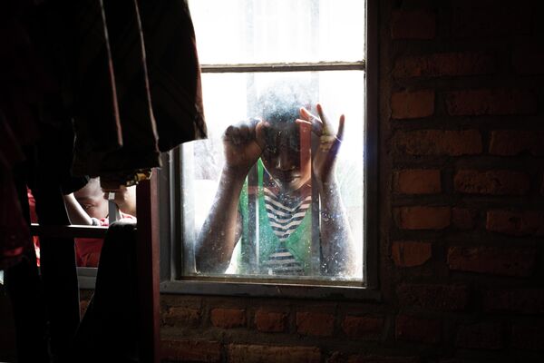 Девушка смотрит в окно транзитного центра Nyarushishi в Западной Руанде