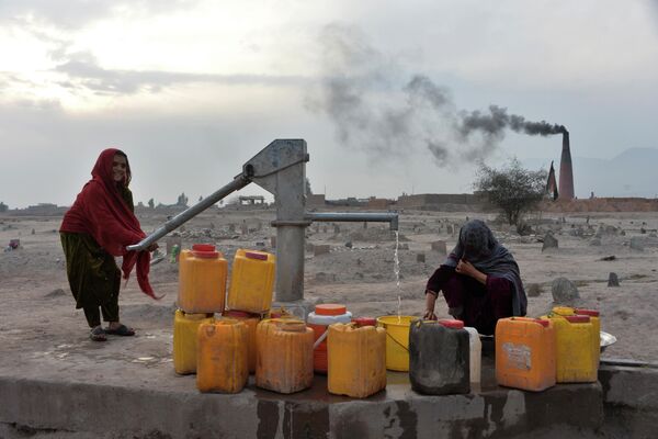 Женщина наполняет канистры питьевой водой в Джелалабаде 