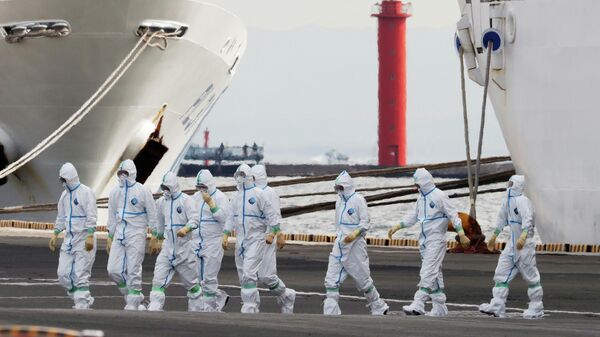Люди в защитных костюмах поднимаются на борт круизного судна Diamond Princess в Йокогаме