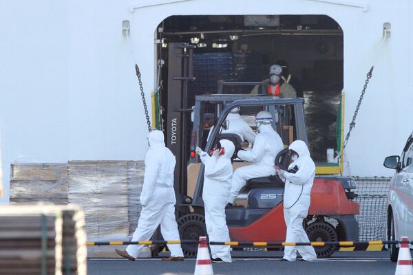 Персонал в защитных костюмах загружает предметы первой необходимости для пассажиров круизного лайнера Diamond Princess в порту Йокогамы