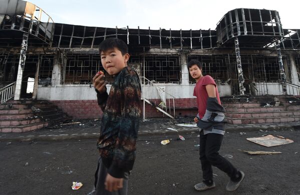 Молодежь проходит мимо сгоревшего здания в селе Масанчи в 250 километрах от Алматы 8 февраля 2020