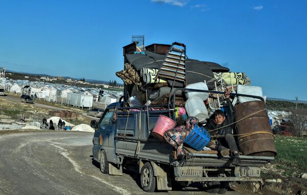 Сирийцы едут в лагерь беженцев, расположенный рядом с границей с Турцией 