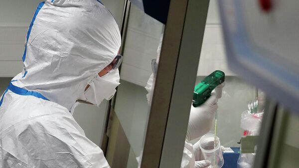 Работник лаборатории во время манипуляций с образцами пробы потенциально зараженного коронавирусом пациента 