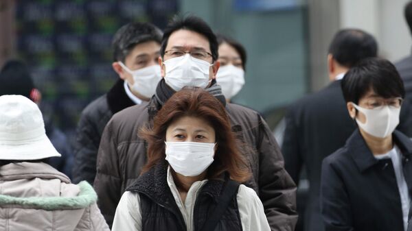 Прохожие в защитных масках на улице Токио, Япония. 17 февраля 2020