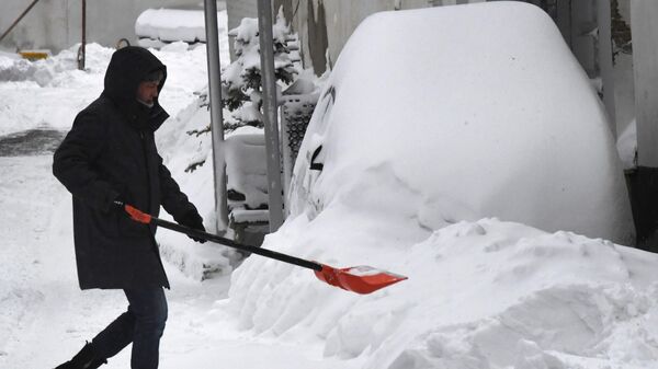 Мужчина убирает снег во Владивостоке