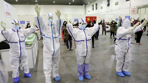 Медицинские работники в защитных костюмах танцуют с пациентами в конференц-центре города Ухань, который был преобразован в импровизированную больницу
