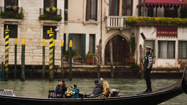 Туристы катаются в гондоле по каналам Венеции