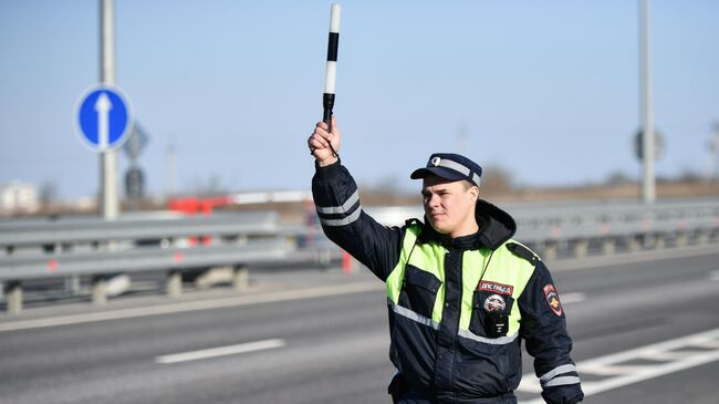 Сотрудник дорожно-патрульной службы подает сигнал водителю об остановке у стационарного поста ДПС