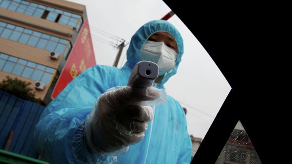 Медицинский работник с термометром на контрольно-пропускном пункте в Китае