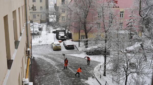Сотрудники коммунальных служб убирают снег во дворе жилого дома