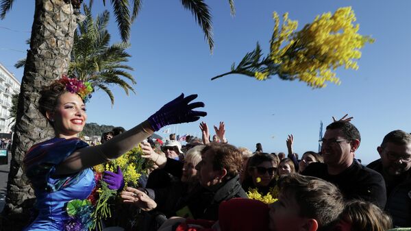Артистка бросает цветы людям во время парада цветов в рамках 136-го карнавального парада в Ницце, Франция