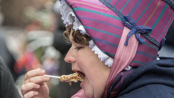 Женщина ест блины во время празднования масленицы