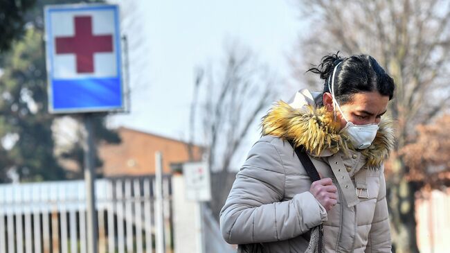 Женщина в защитной маске покидает больницу Кодоньо в северной Италии