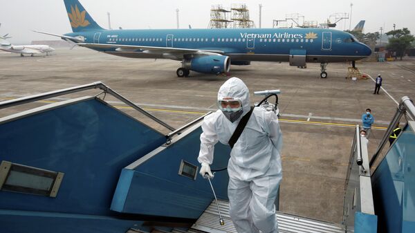 Работник распыляет дезинфицирующее средство на трапе самолета Вьетнамских авиалинии для защиты от недавней вспышки коронавируса в аэропорту Ной Бай в Ханое, Вьетнам 