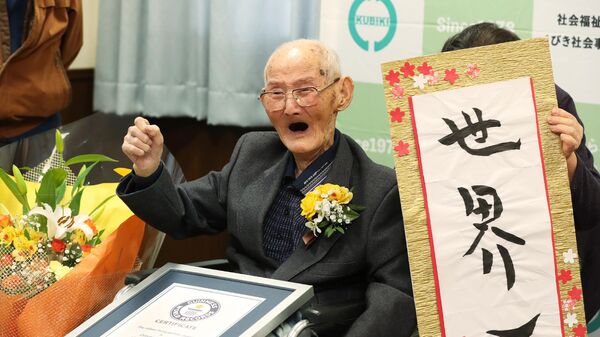 112-летний японец Ватанабэ Титэцу позирует рядом с наградным знаком как самому старому из ныне живущих мужчин