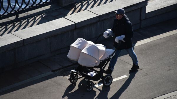 Мужчина с детской коляской идет по набережной