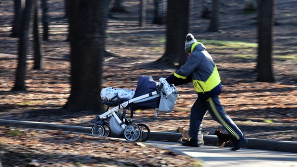 Мужчина с детской коляской гуляет по парку