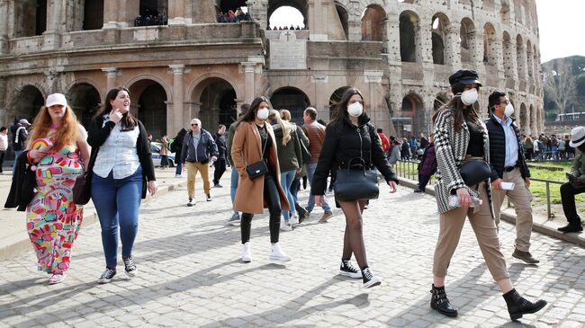 Люди в защитных масках у Колизея в Риме, Италия