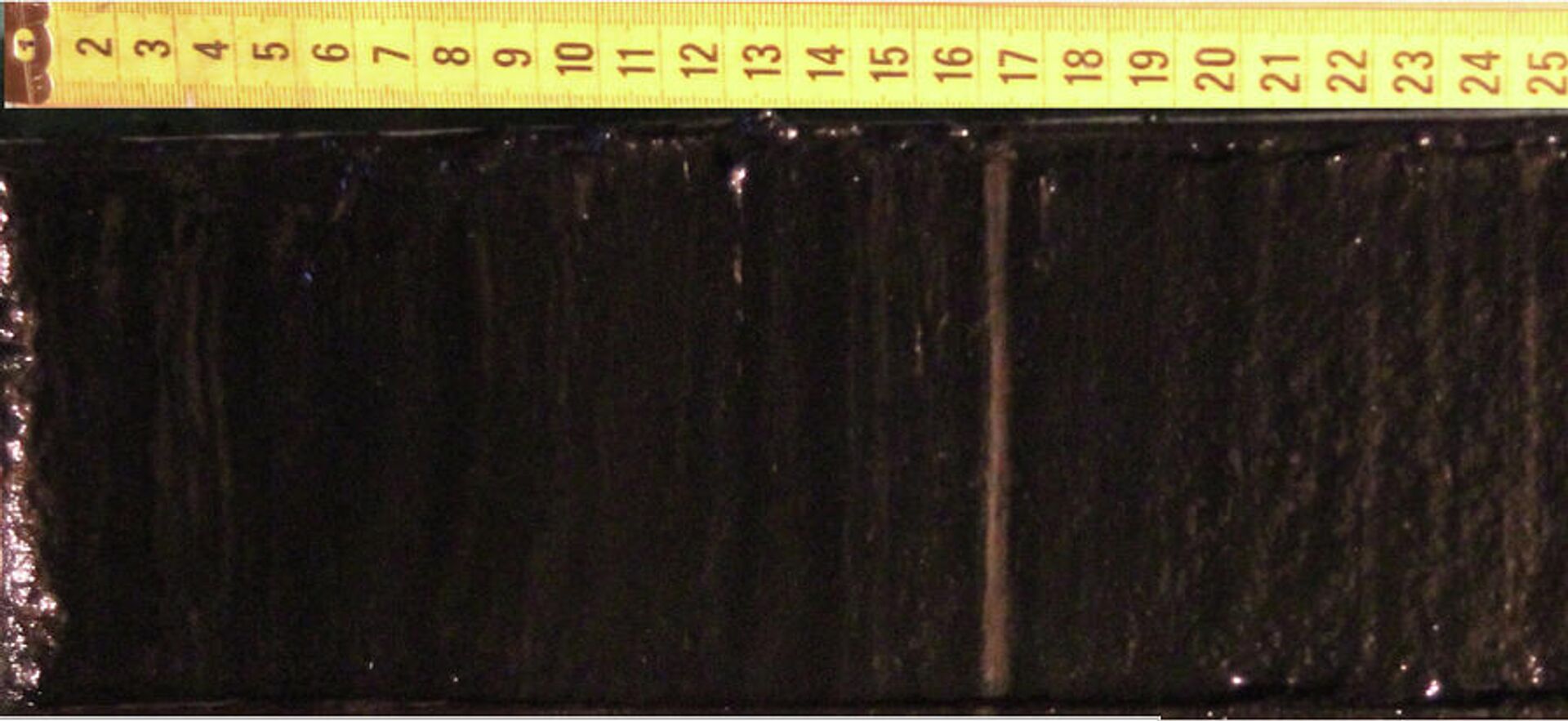 Поверхность вскрытого керна отложений озера Заповедное. На фоне темноокрашенных глин отчетливо виден слой светлого цвета, датируемый 1908-1910 годами - РИА Новости, 1920, 26.05.2023