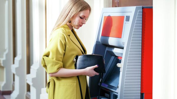 Девушка снимает деньги в банкомате