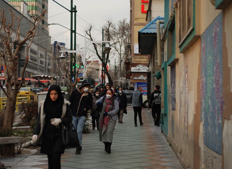 Люди в медицинских масках на улице столицы Ирана города Тегеран