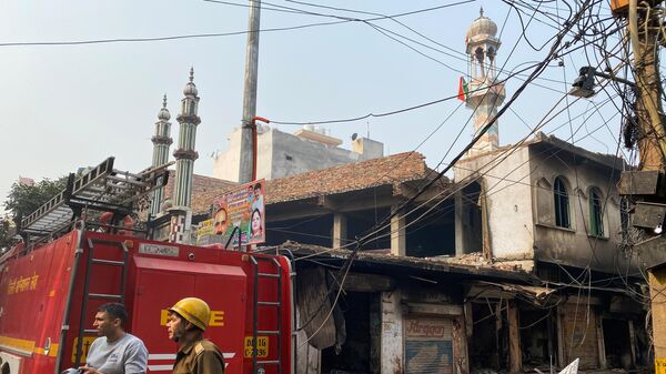 Пожарные около сгоревшей мечети в Нью-Дели 
