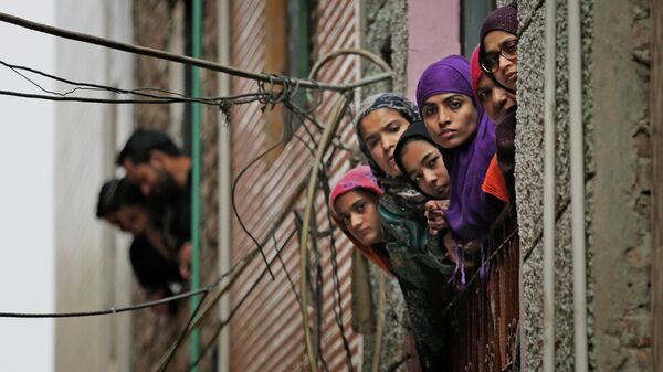 Индийские мусульманки выглядывают в окно во время патрулирования сотрудниками службы безопасности улицы в Нью-Дели