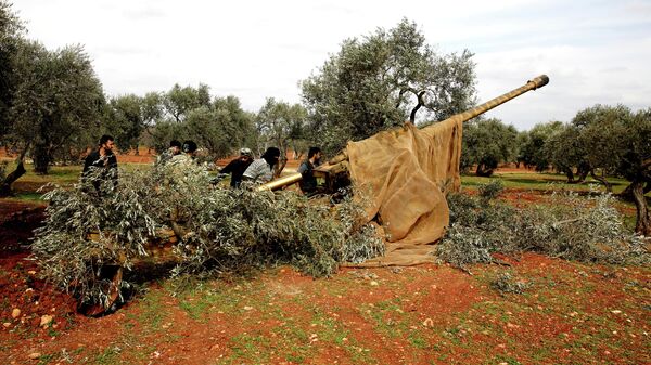 Сирийские боевики заряжают орудие в провинции Идлиб
