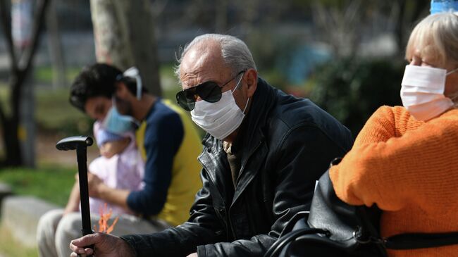 Люди, одетые в защитные маски, около больницы AHEPA, где проходит лечение первый пациент с подтвержденным   коронавирусом в Салониках, Греция