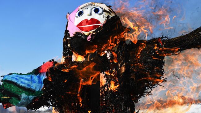 Сжигание чучела во время празднования Широкой Масленицы на озере у жилого массива Юго-Западный в городе Новосибирске