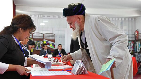 Житель Душанбе получает бюллетень на избирательном участке, чтобы проголосовать на выборах в нижнюю палату парламента Таджикистана. 1 марта 2020