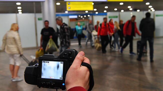 Сотрудник санитарно-карантинного пункта проводит дистанционную термометрию пассажиров, прибывших в международный аэропорт Шереметьево