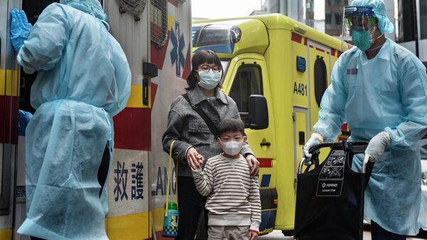 Женщина с ребенком в защитных масках рядом с автомобилем скорой помощи в Гонконге