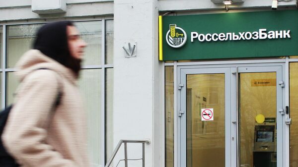 Прохожий около входа в офис банка Россельхозбанк на одной из улиц в Москве