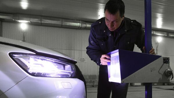 Технический эксперт проводит осмотр автомобиля на пункте техосмотра в Новосибирске