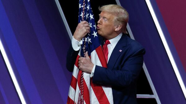 Президент США Дональд Трамп целует американский флаг после выступления на Конференции консервативных политических действий