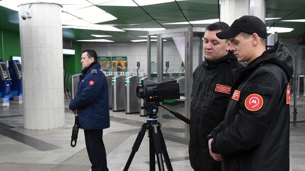 Сотрудники метрополитена проверяют у пассажиров московского метро температуру с помощью тепловизора