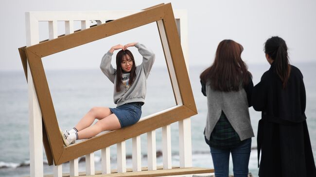 Девушки фотографируются на пляже Gyeongpo Beach в городе Каннын, Республика Корея