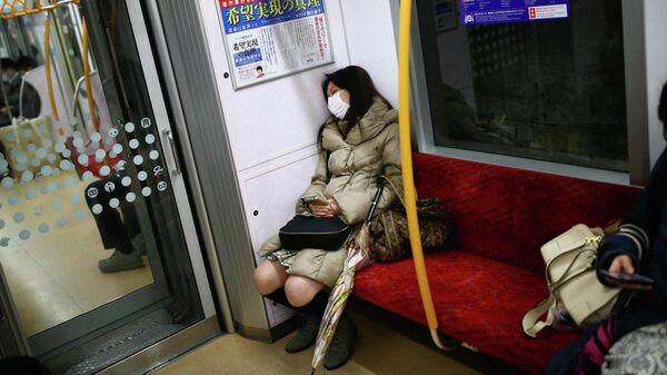 Женщина в медицинской маске  в поезде в Токио, Япония