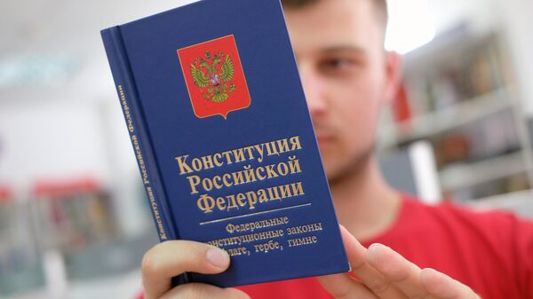 Молодой человек держит Конституцию РФ