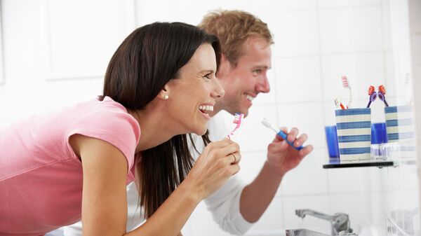 Пара чистит зубы перед зеркалом