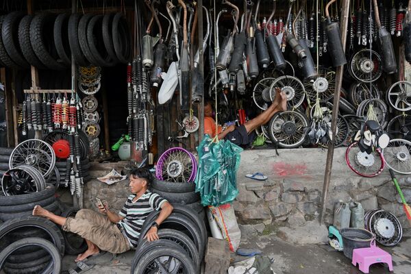 Мужчины ожидают клиентов в своей мастерской по ремонту мотоциклов в Джакарте