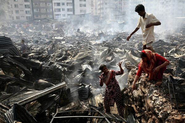 Обитатели трущоб разыскивают предметы домашнего обихода, сохранившиеся после пожара в Дакки, Бангладеш