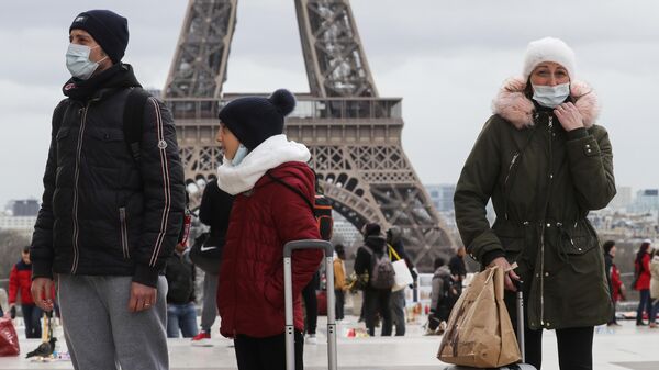 Люди в защитных масках на фоне Эйфелевой башни в Париже