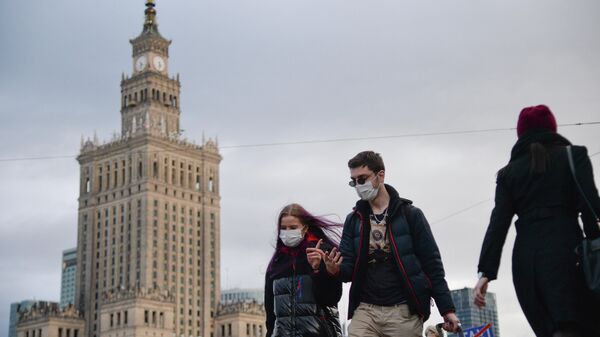 Прохожие в медицинских масках на улице в Варшаве