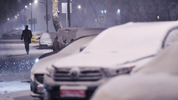 Мужчина идет по улице во время снегопада в Москве