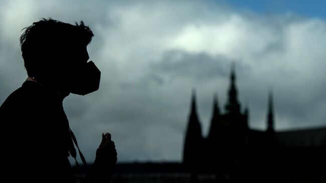 A tourist wearing a face mask walks across the Charles Bridge on March 12, 2020 in Prague. - The Czech government imposed a ban on all events with more than 100 people in the EU country of 10.7 million people, closing museums and galleries as well as cinemas and theatres. Czech Health Minister Adam Vojtech also said that foreigners entering the country, including ordinary tourists, would be tested and may end up in quarantine. (Photo by Michal Cizek / AFP)