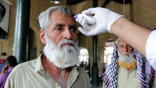 Медицинский работник проверяет температуру тела пассажира на железнодорожной станции в Карачи, Пакистан