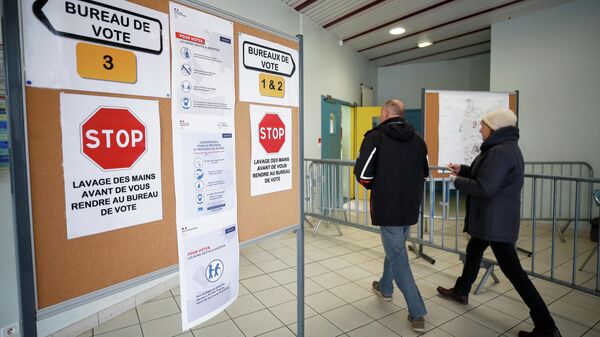 Участники голосования проходят мимо объявлений на избирательном участке в Краке во время первого тура муниципальных выборов во Франции