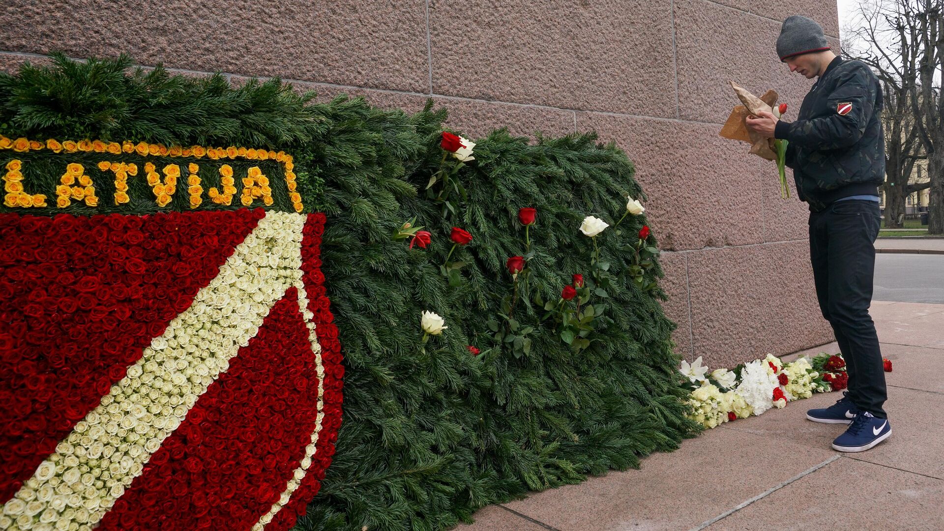 Сторонник латышского легиона Ваффен СС возлагает цветы к памятнику Свободы в Риге по случаю дня памяти латышского легиона Ваффен СС - РИА Новости, 1920, 18.03.2021